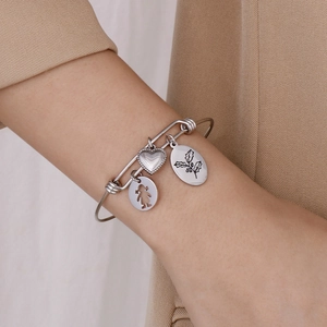 Detailed view of silver charm bracelet with heart and floral pendants worn on wrist
