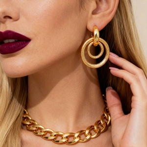 Detail of matte gold geometric double hoop earrings worn by a model in a close-up view