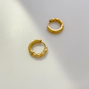 Detailed view of golden twisted hoop earrings featuring abstract geometric enamel lines