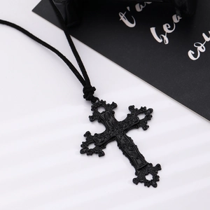 Macro view of gothic black cross necklace with ornate floral pattern engraving