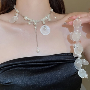 Detailed view of pearl shell tassel necklace and earrings set on elegant evening dress