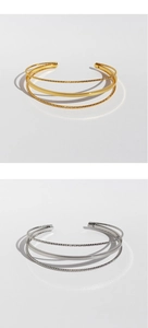 Detail of multi-layer geometric open bracelets in gold and silver finish with twisted texture