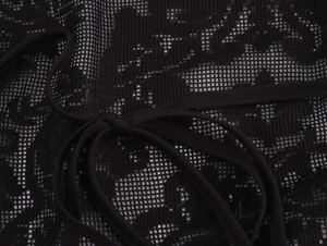 Close-up of black lace fabric with intricate mesh patterns and delicate halter neck strap
