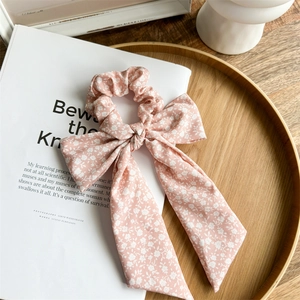 Detailed shot of pink floral bow scrunchie with ribbons on a rustic wooden tray
