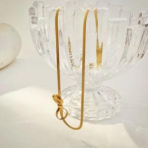 Detailed macro view of 18K gold snake chain earrings with elegant bow knot on glass rim