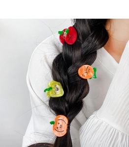 Close-up of colorful fruit and vegetable shaped hair clips on a black braided hairstyle