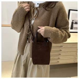 Brown faux suede leopard style crossbody bag shown worn by a model in a modern home setting
