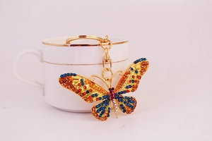 Detail of a golden butterfly keychain with colorful rhinestones on a ceramic cup
