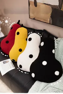 Detail of four colorful pear-shaped plush cushions with polka dots on a sofa