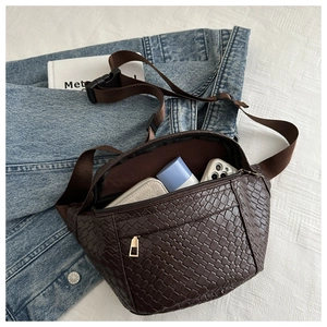 Detail view of woven brown waist bag texture with everyday items on a white surface