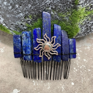 Detail of blue lapis lazuli crystal hair comb with golden sun emblem on mossy rock
