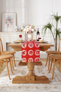 Detail of red festive table runner with cartoon fortune patterns on a wooden dining table