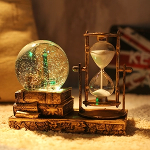 Detail view of retro hourglass and Eiffel Tower crystal ball on vintage book base decoration