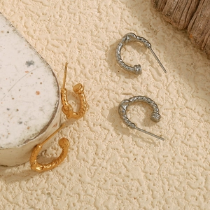Detailed macro view of spiral twisted hoop earrings in gold and silver stainless steel
