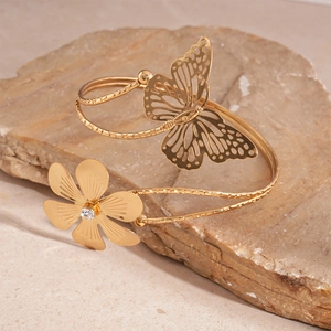 Elegante bracciale rigido aperto in oro con farfalla traforata e dettagli floreali