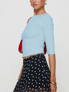 Slim fit light blue short sleeve knit top paired with a polka dot skirt and red handbag