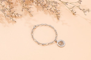 Detail of silver chain bracelet with heart-shaped sparkling star pendant on orange surface