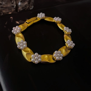 Detailed macro view of vintage gold matte metal chain with elegant pearl flower accents