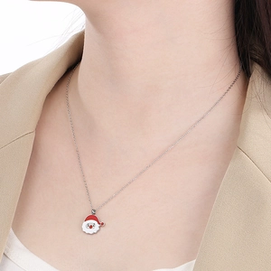 Detail of silver chain necklace featuring Santa Claus pendant worn with a beige suit