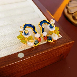 Detail of vintage flower earrings with blue enamel and pearls in a wooden jewelry box