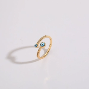 Close-up of golden spiral open ring with sparkling zircon and blue evil eye charms
