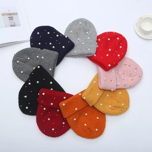 Detailed flat lay of knitted beanies with pearls in multiple colors on white background