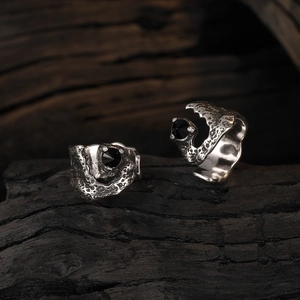 Gothic vintage silver texture ear cuffs with black zircon in artistic dark still life photography