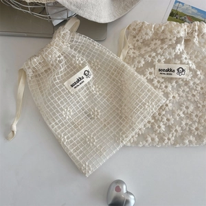 Detail of floral lace mesh drawstring bags with daisy embroidery and delicate ribbon ties