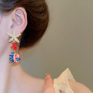 Detail of starfish earring with red coral beads and colorful fish pendant on model