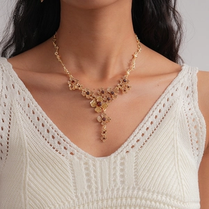 Detail of vintage gold flower necklace with red rhinestones on a female model