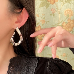 Close-up of polished silver twisted U-shaped drop earring worn by a model