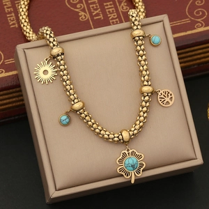 Detail of turquoise clover and Tree of Life charms on a golden beaded chain necklace