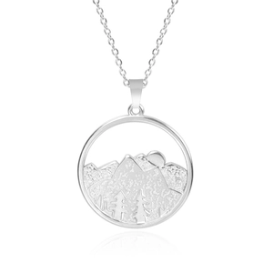 Macro shot of silver stainless steel round pendant with detailed mountain and sun engraving