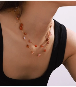 Detail of a double-layer beaded necklace with reddish-brown stones on a gold chain