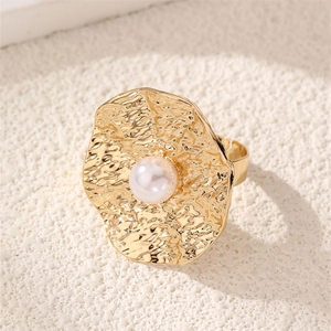 Close-up of vintage golden ring with hammered texture and a white pearl on stone base