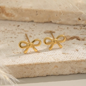 Elegant 18K gold-plated stainless steel bow earrings on a natural stone base with feathers