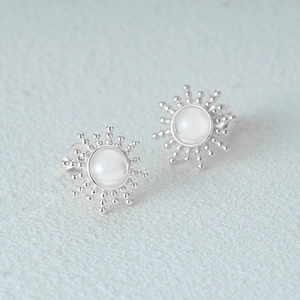 Macro detail of sun-shaped 925 sterling silver stud earring with white opal stone