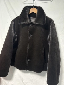 Detail of faux fur collar and button closure on dark brown reversible shearling jacket