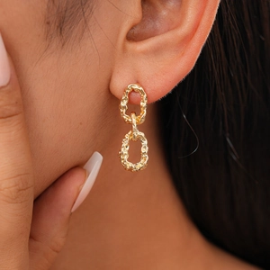 Gros plan de boucles d'oreilles dorées à maillons texturés sur un mannequin