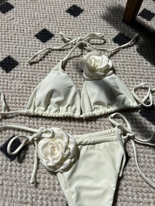 Detailed view of 3D rose flower accents on cream white string bikini swimwear