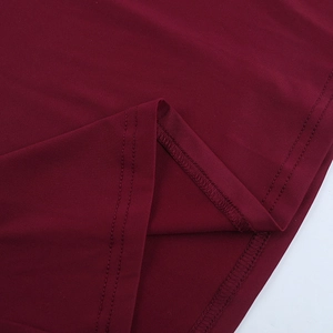 Macro view of double-stitched hem and fine knit texture on burgundy evening gown