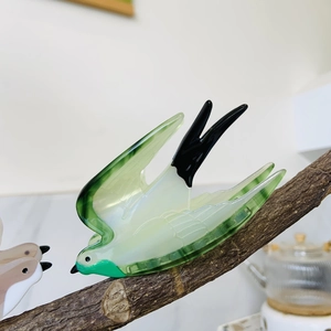 Acetate swallow hair claw clip in gradient green and cream, perched on a branch