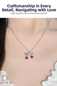 Vista ravvicinata della collana con ciliegia, fiocco d'argento e perline rosse sul collo