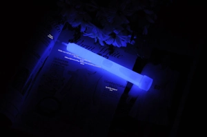 Detail view of a 6-inch blue glow stick illuminating a dark scene for camping or events