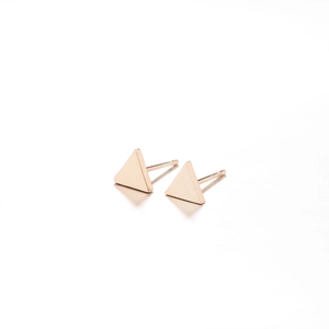 Macro view of gold minimalist triangle stud earrings with smooth metallic finish