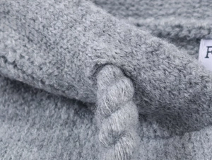 Close-up of thick twisted drawstring and brand tag on grey star jacquard knit cardigan