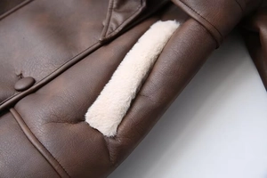 Close-up of dark brown leather jacket showing thick cream faux fur lining details