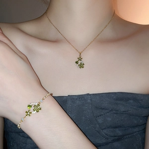 Detail view of 18k gold plated necklace and bracelet with green clover pendant and small diamonds