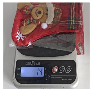 Petit sac cadeau de Noël rouge mesuré sur une balance de cuisine numérique à 14 grammes