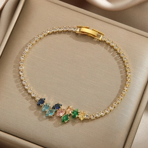 Elegant gold tennis bracelet with colorful leaf-shaped rhinestones on a satin gift box